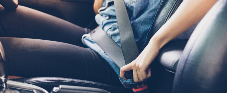 Asian woman fastening seat belt in the car, safety concept