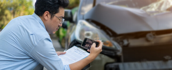 insurance adjuster taking pictures of damaged car