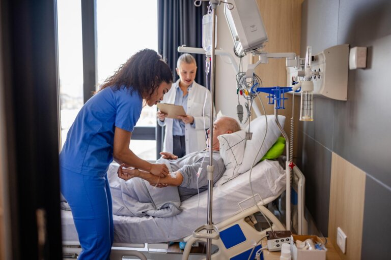 Senior man receiving medical care in hospital with healthcare professionals assisting in recovery process