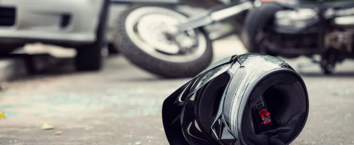 Close-up of a helmet of a driver with a blurred motorbike and car in the background