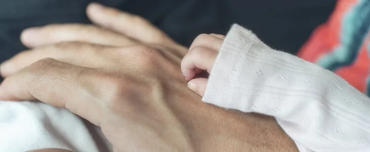 A father holding his newborn daughter's hand