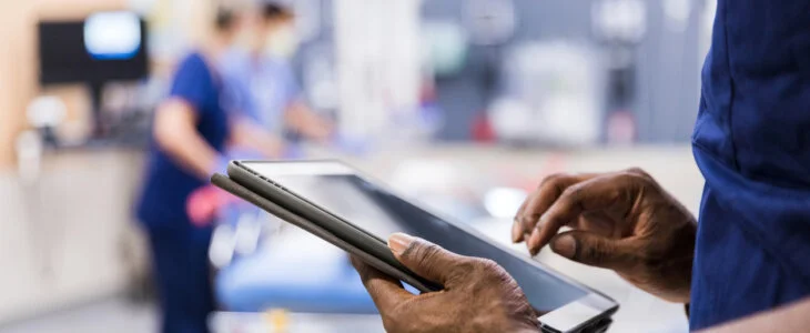 The unrecognizeable medical staff uses digital tablet to review medical chart.