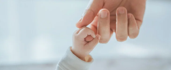 Close-up little hand of child baby holding hand of mother, A newborn holds on to mom's, dad's finger, Love and relationship with infant, Care and support, Dreaming and protection