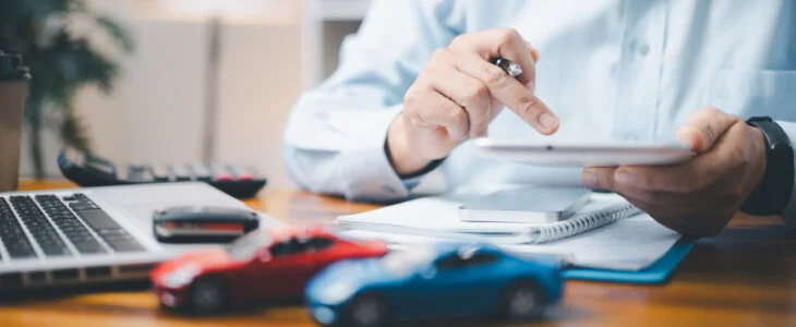 Toy Car In Front Of Businessman Calculating Loan. Saving money for car concept, trade car for cash concept, finance concept.