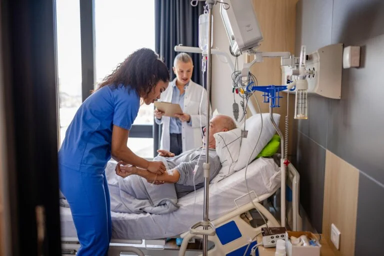 Senior man receiving medical care in hospital with healthcare professionals assisting in recovery process